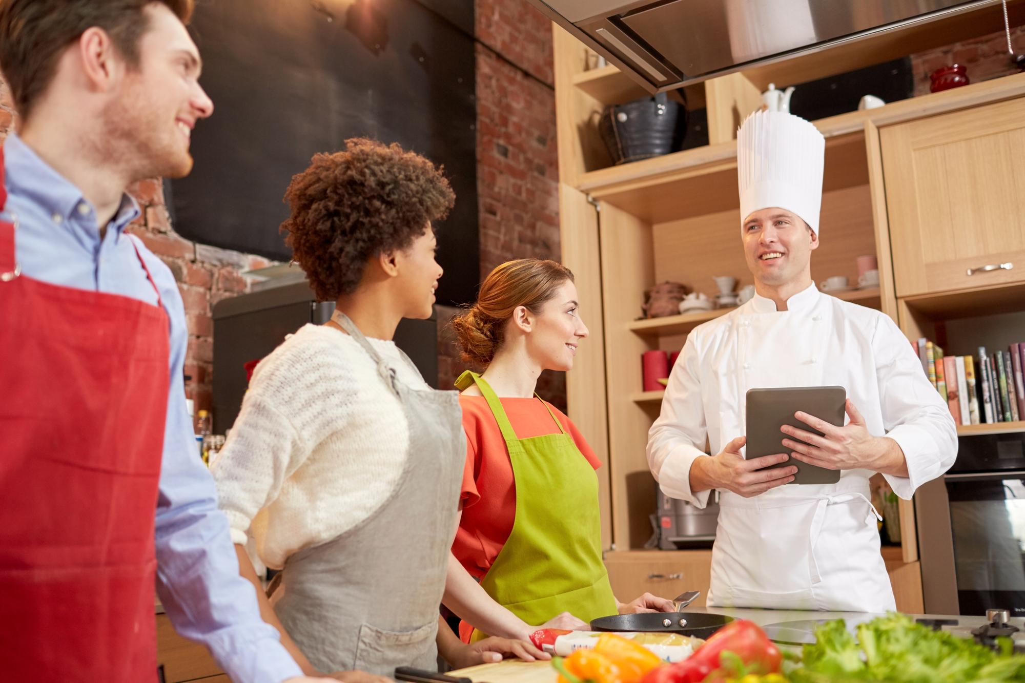 Instructor speaking to a small class in modern kitchen